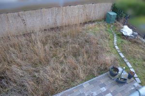 Garten mit Wildwuchs mit Terrassenecke vorm Umgraben